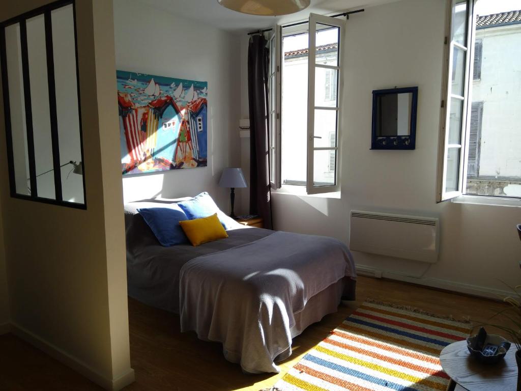 a bedroom with a bed in a room with windows at Le studio de Line in Rochefort