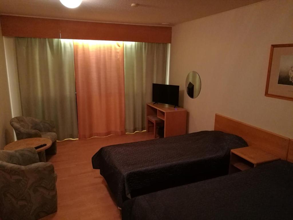 Habitación de hotel con cama y TV en Hotelli Lohikontti, en Parikkala