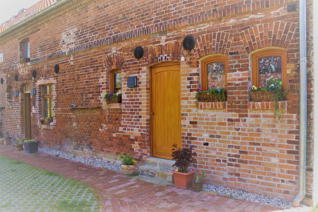 a brick building with a yellow door and windows at An den Elbwiesen Gästezimmer "Weißstorch" Nur Nichtraucher in Greudnitz