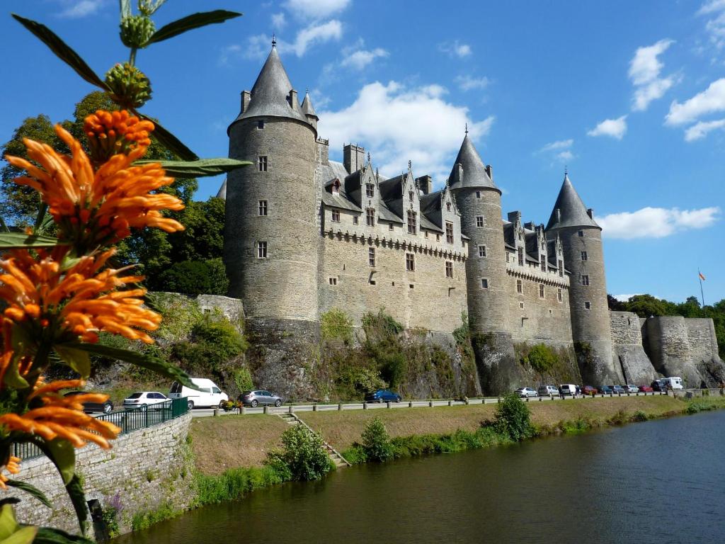 a castle on the side of a river at JOSSELIN CHURCH VIEW . in Josselin