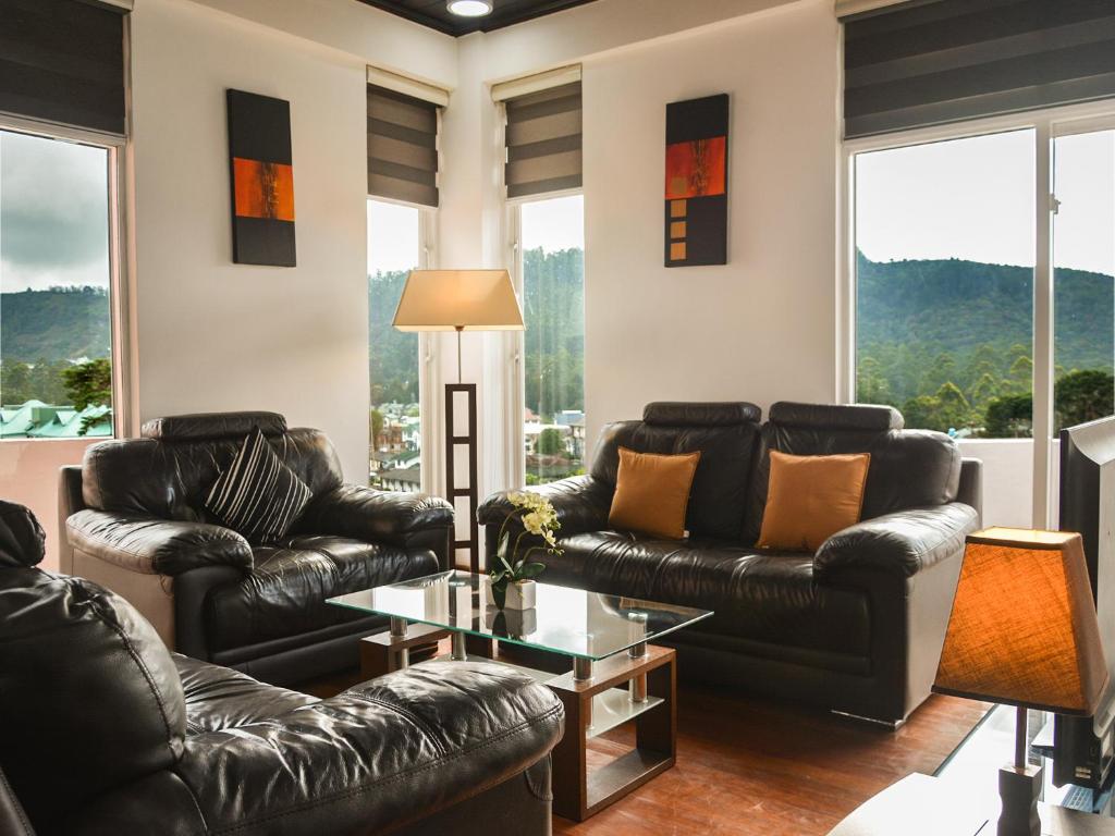 a living room with leather couches and a table at Panoramic Holiday Apartment / Seagull Complex | Nuwara Eliya in Nuwara Eliya