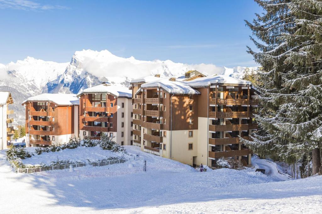 un hotel en la nieve con montañas cubiertas de nieve en Résidence Odalys Le Buet en Morillon