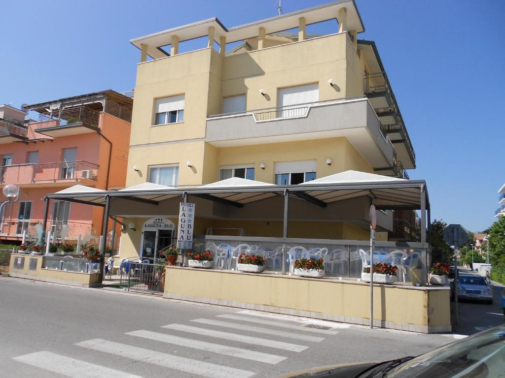 un restaurant avec des parasols en face d'un bâtiment dans l'établissement Hotel Laguna Blu, à Rimini