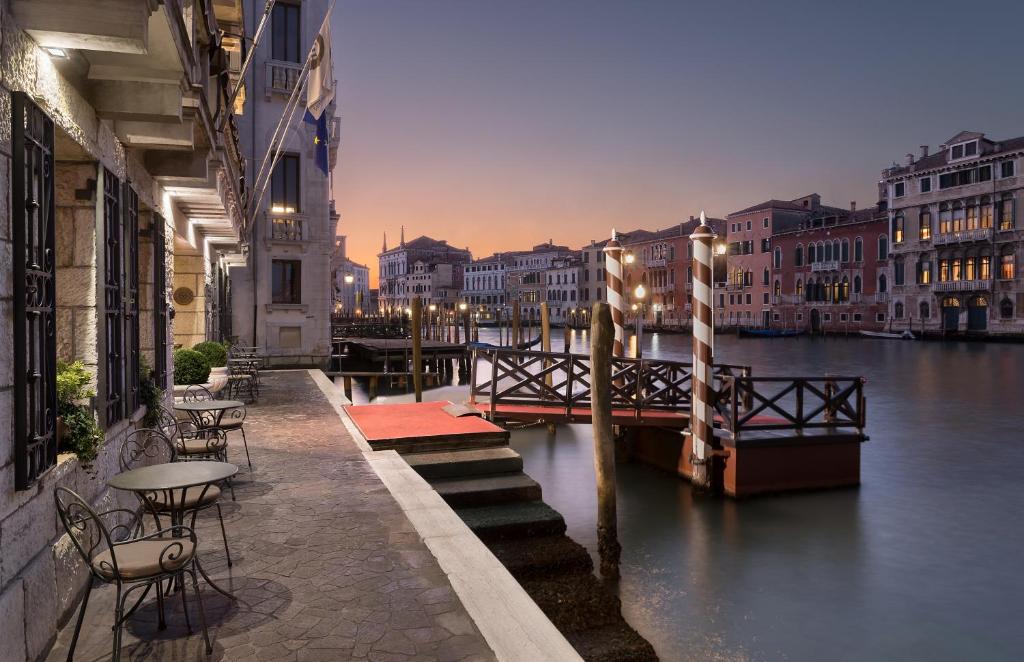 a canal with tables and chairs next to a river at Sina Palazzo Sant'Angelo in Venice