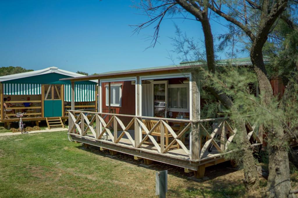 a tiny house with a porch in a yard at Camping Lido in Bibione