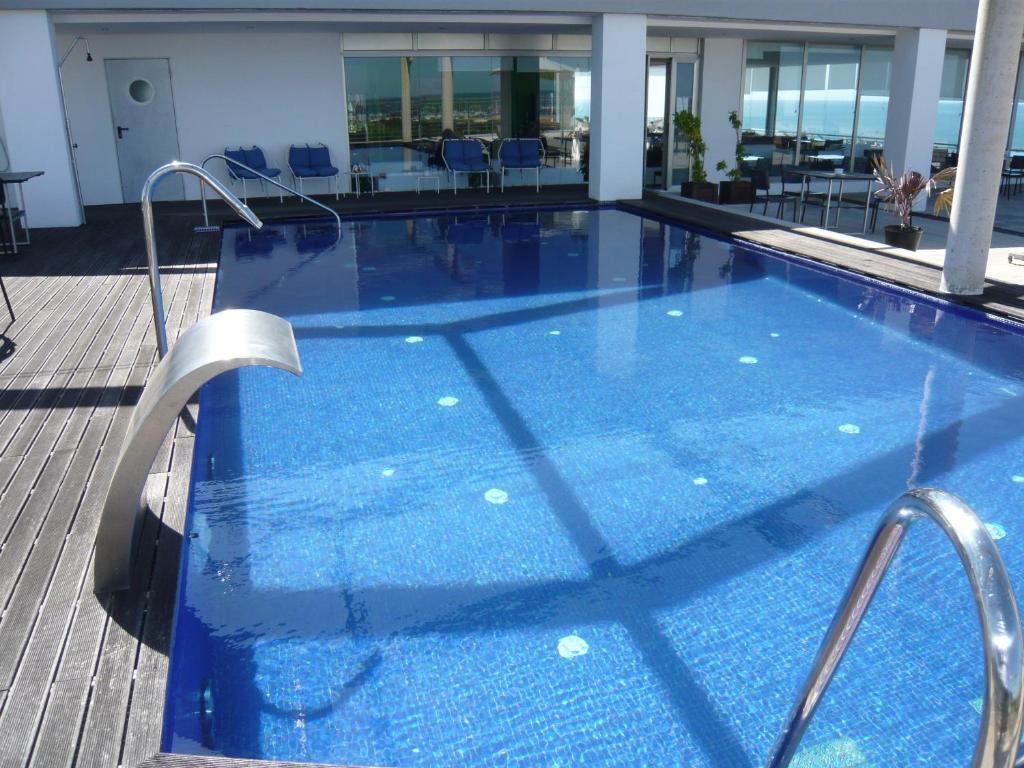 a large blue swimming pool with chairs and tables at Mazagonia in Mazagón