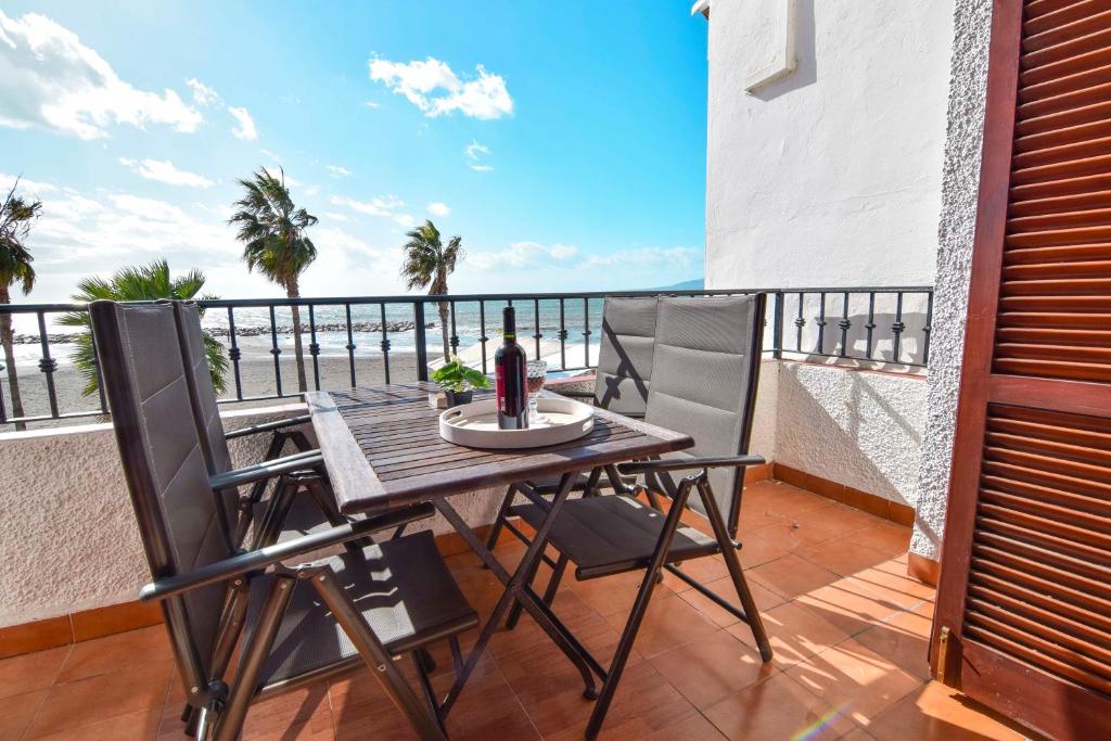 una mesa y sillas en un balcón con vistas al océano en Letmalaga Cremades Seaside, en Málaga