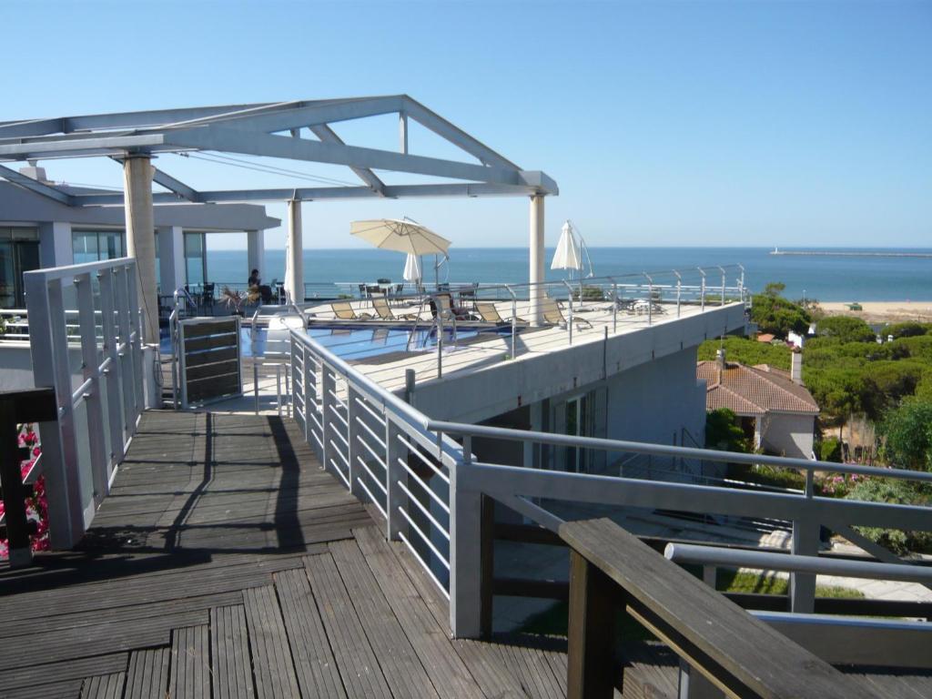 a boardwalk with a swimming pool and an ocean at Mazagonia in Mazagón