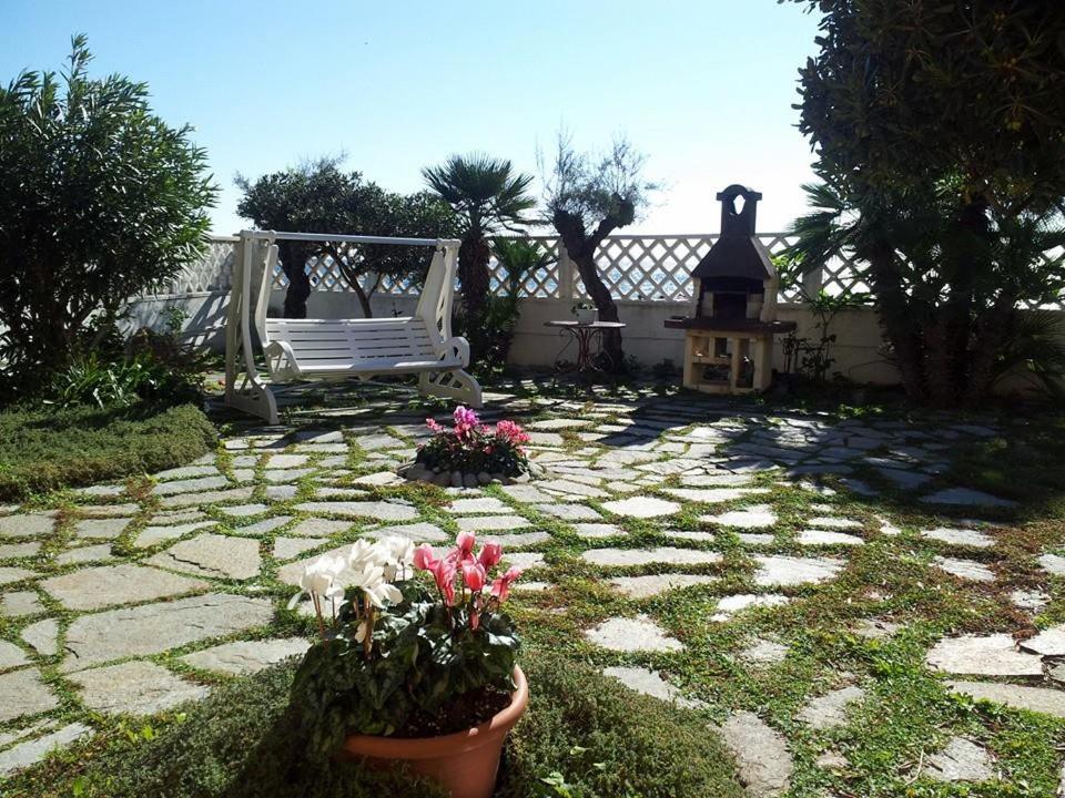 un jardín con un banco y flores y un camino de piedra en il giardino sul mare B&B, en Riva Ligure