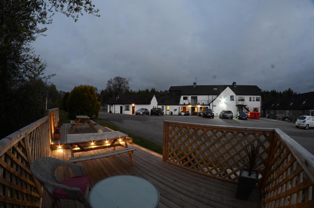 una terraza de madera con una mesa y luces. en Achilty Guest House, en Contin