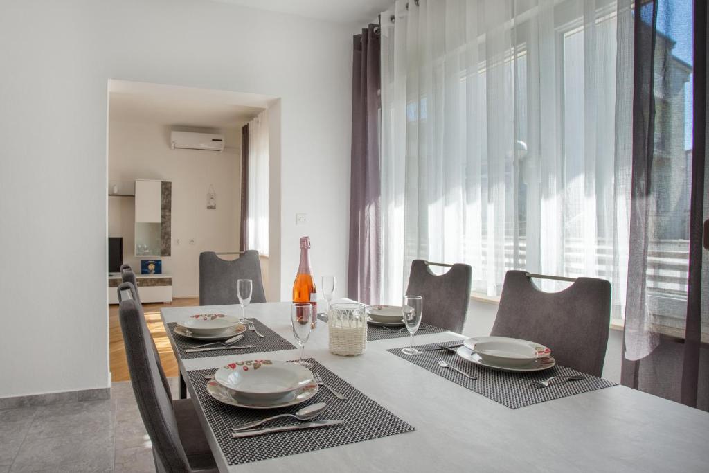 a dining room with a table with plates and wine glasses at Apartment Blaž in Split