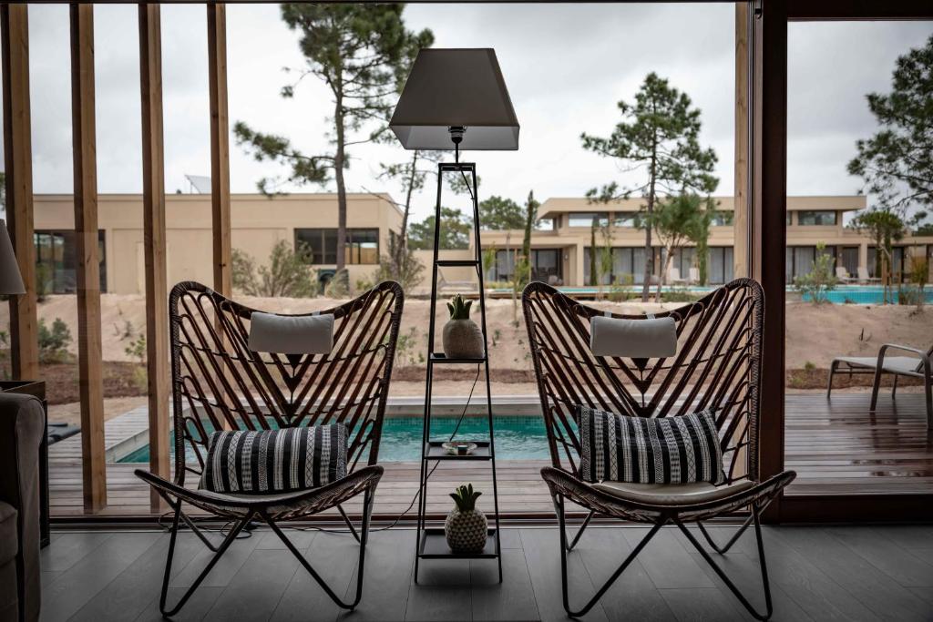 two rocking chairs sitting on a porch with a pool at Pestana Troia Eco-Resort & Residences in Troia