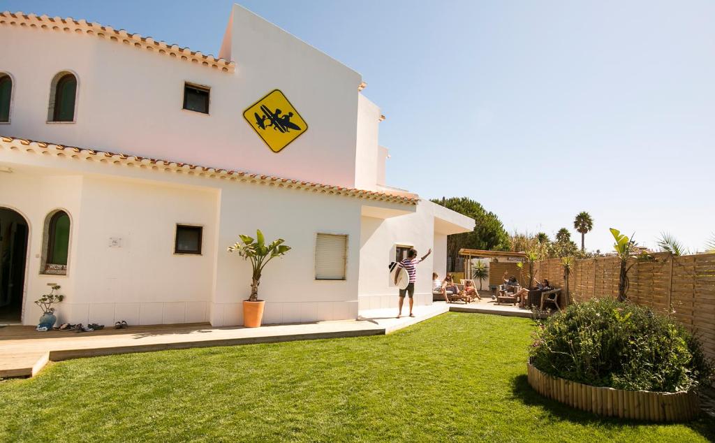 une personne debout dans la cour d'une maison dans l'établissement Algarve Surf Hostel - Sagres, à Sagres