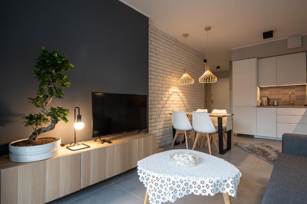 ein Wohnzimmer mit einem TV und einem Tisch sowie eine Küche in der Unterkunft City Lights Rakowicka 15 in Krakau
