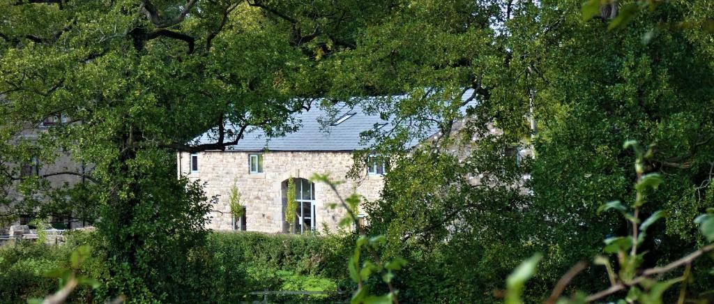 una casa de piedra con techo azul y árboles en Lancaster Barn en Lancaster