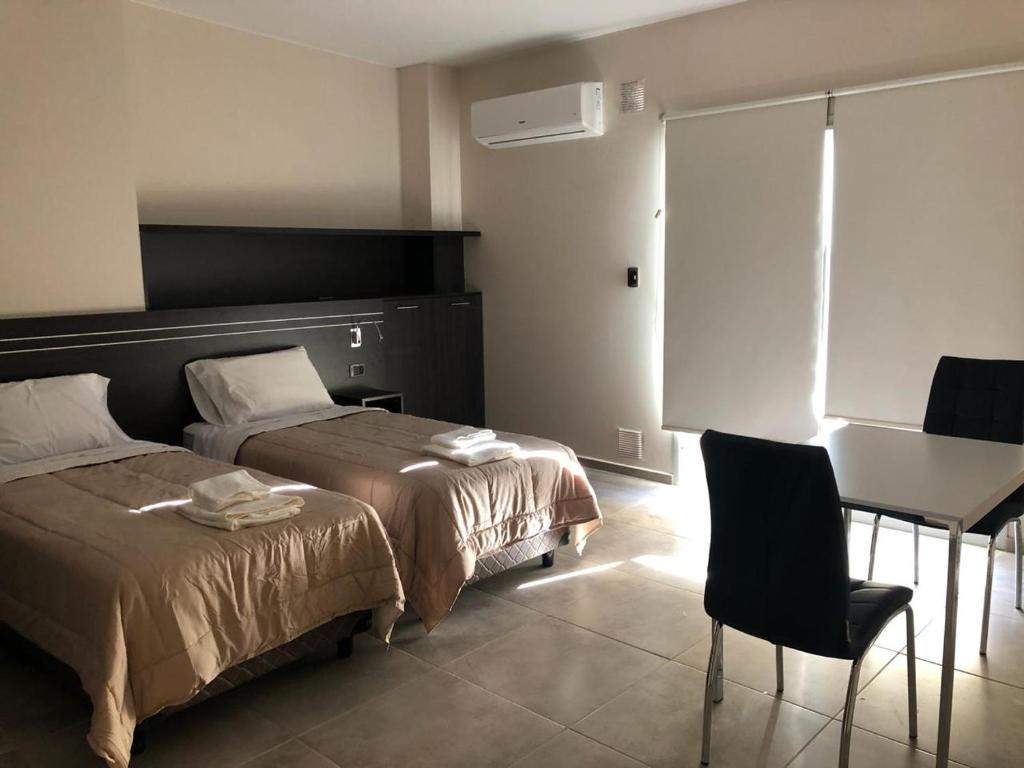Un dormitorio con dos camas y una mesa y un escritorio. en Complejo Edificio Rosario, en San Juan