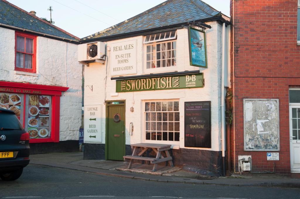 a shop with a bench in front of it on a street at The Swordfish Inn in Penzance