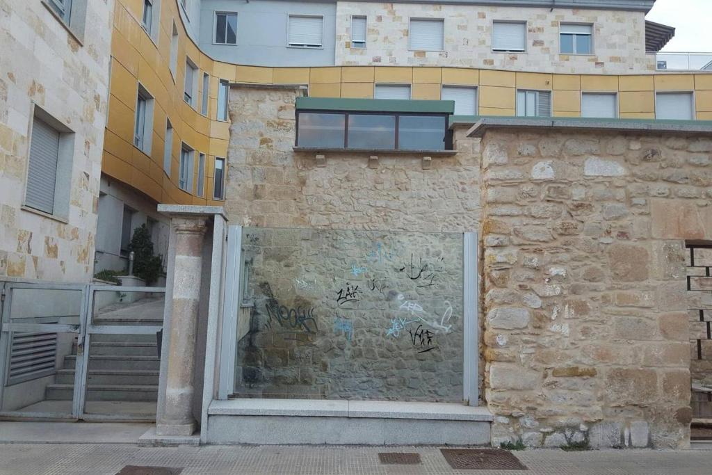 a brick wall with graffiti on it next to a building at Piso en la ruta del Románico in Zamora