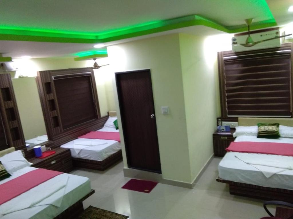 Highland Inn Hotel في منغالور: غرفة بثلاث اسرة عليها اضاءات خضراء