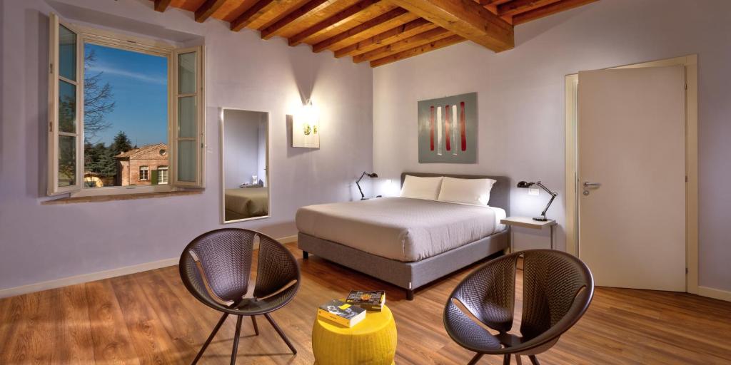 een slaapkamer met een bed en 2 stoelen bij Hotel Cortaccia Sanvitale in Sala Baganza