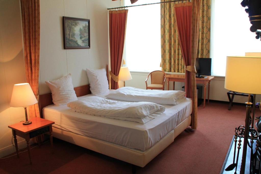 a bedroom with a bed and a desk and a window at De Doelen in Leiden