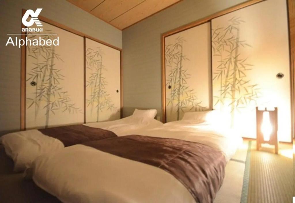 Un dormitorio con una cama grande y una pared con árboles. en Alphabed Takamatsu Kitahama EAST 202 / Vacation STAY 20102, en Takamatsu