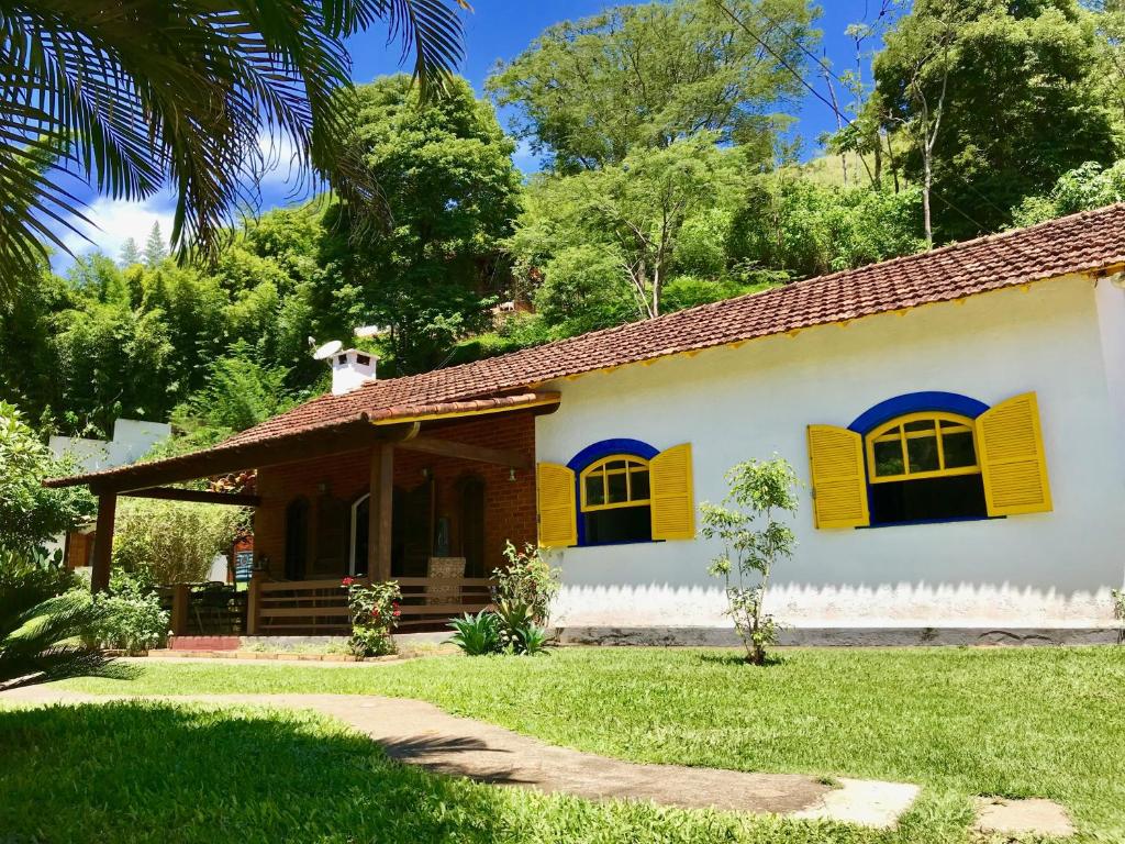 een huis met gele luiken en een tuin bij Hostel 040 in Itaipava