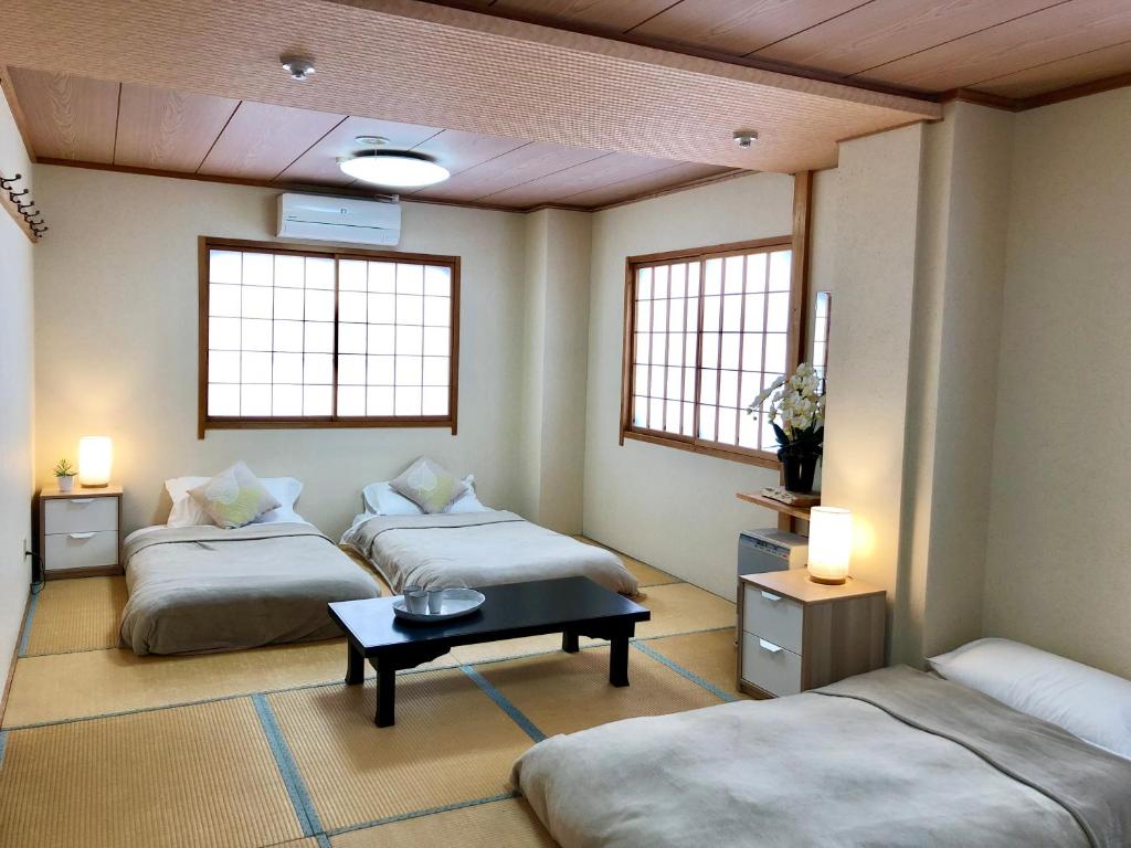 a room with two beds and a table and two windows at Akakura Akarien in Myoko