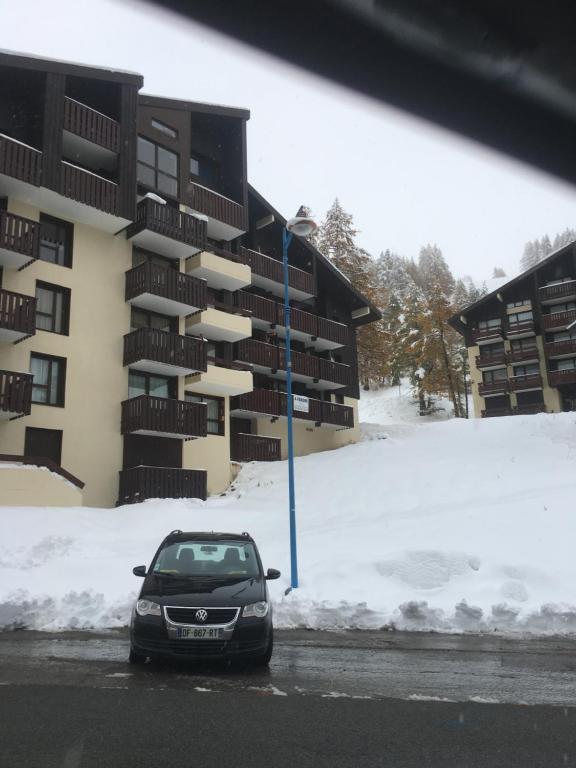 イゾラ 2000にあるLe Petit Marmottonの雪の中の建物の前に停車する車