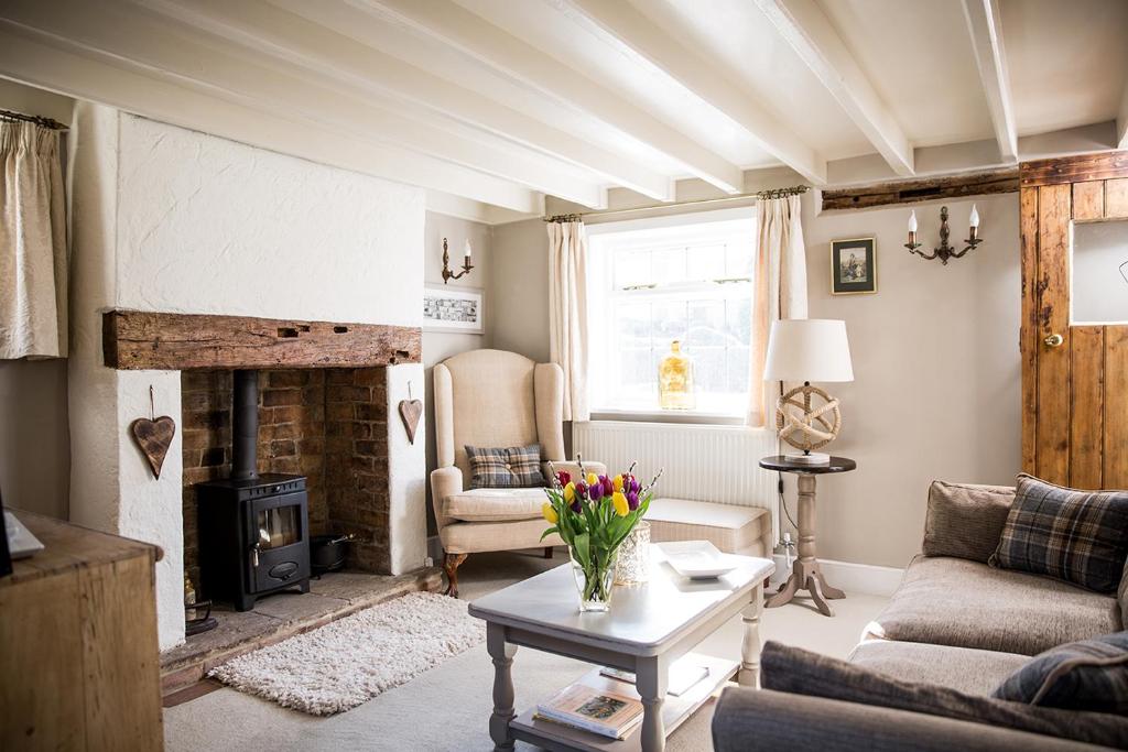 ein Wohnzimmer mit einem Sofa und einem Kamin in der Unterkunft The Cottage, Gretton (Cotswolds) in Gretton