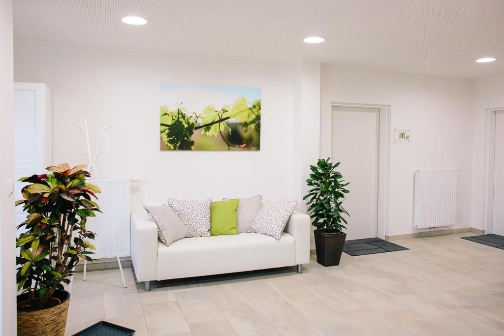 a living room with a white couch and two plants at Steira-Studios in Ehrenhausen