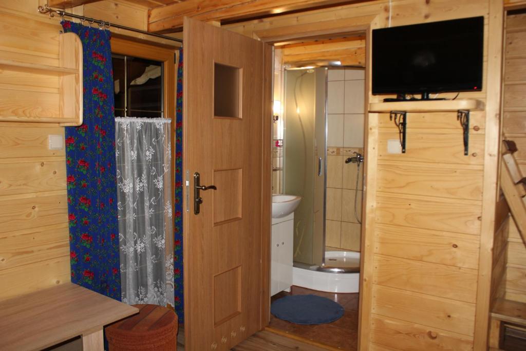 baño con aseo y TV en una cabaña de madera en Ranczo w Dolinie, en Kościelisko