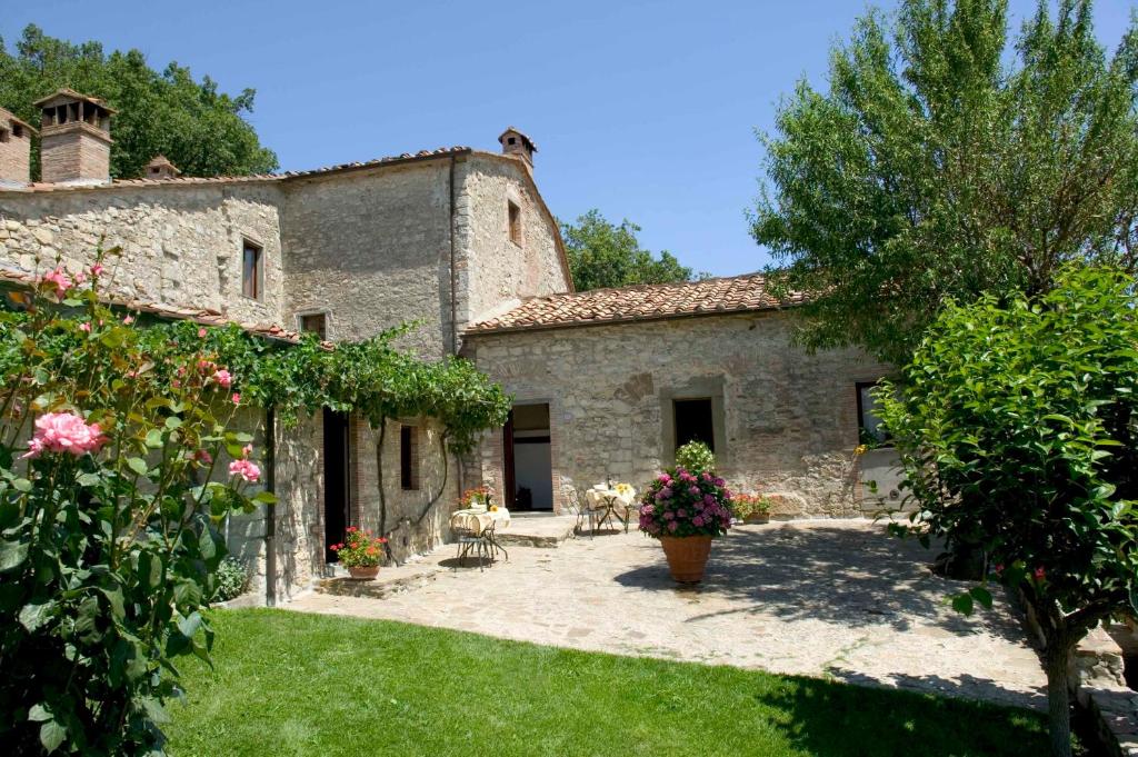 uma vista exterior de uma casa de pedra com um quintal em Querceto Di Castellina em Castellina in Chianti