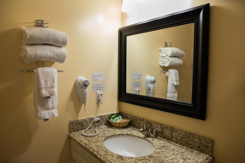 ein Badezimmer mit einem Waschbecken, einem Spiegel und Handtüchern in der Unterkunft Tea Garden Lodge in South Lake Tahoe