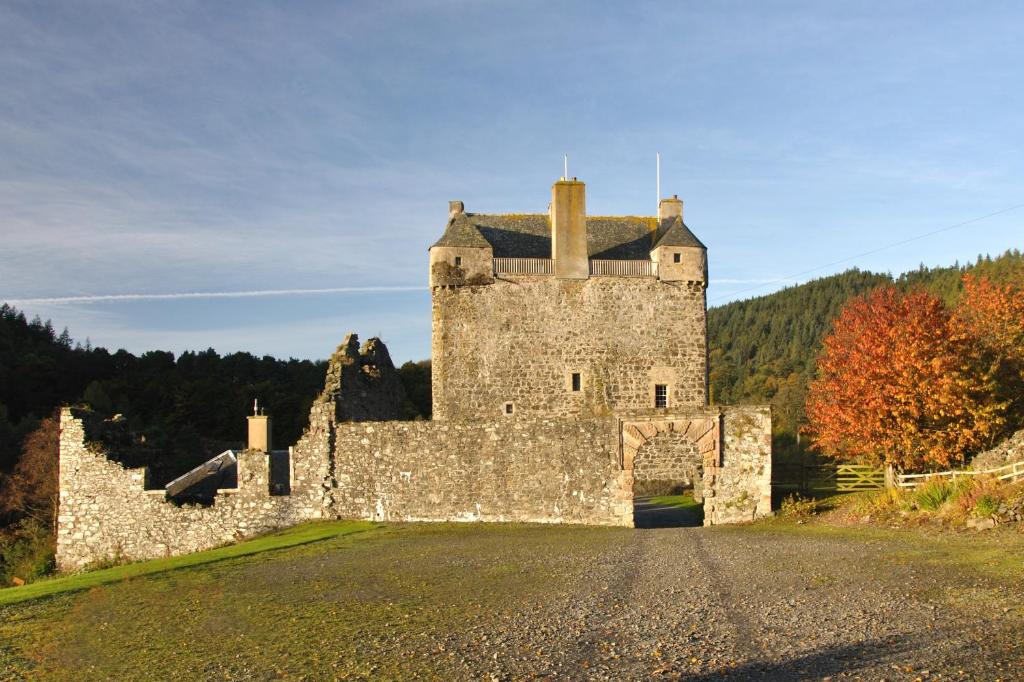 ein altes Schloss auf einem Hügel mit einer Straße in der Unterkunft Neidpath Castle Cottage in Peebles