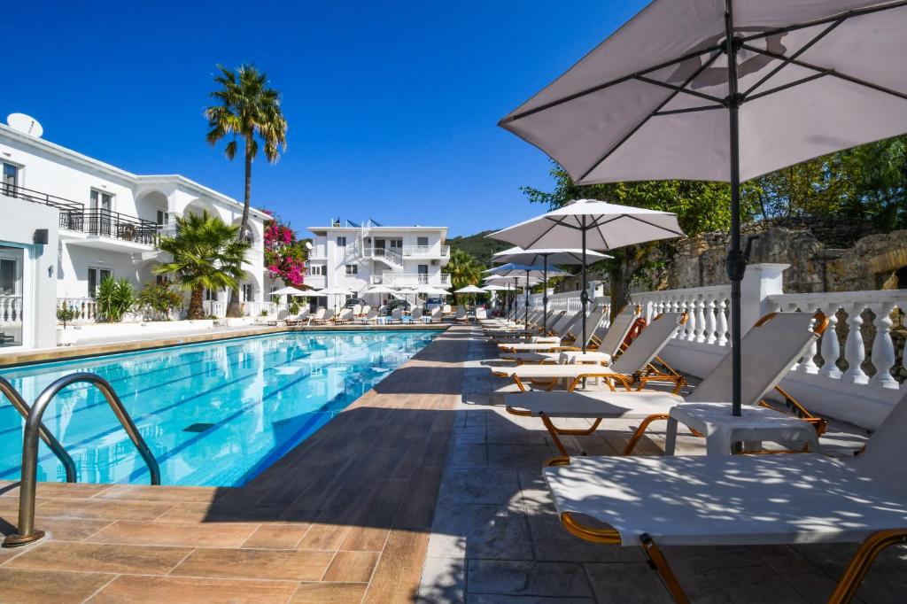 a pool with chairs and umbrellas next to a hotel at Kalamaki Zakynthos Apartments in Kalamaki