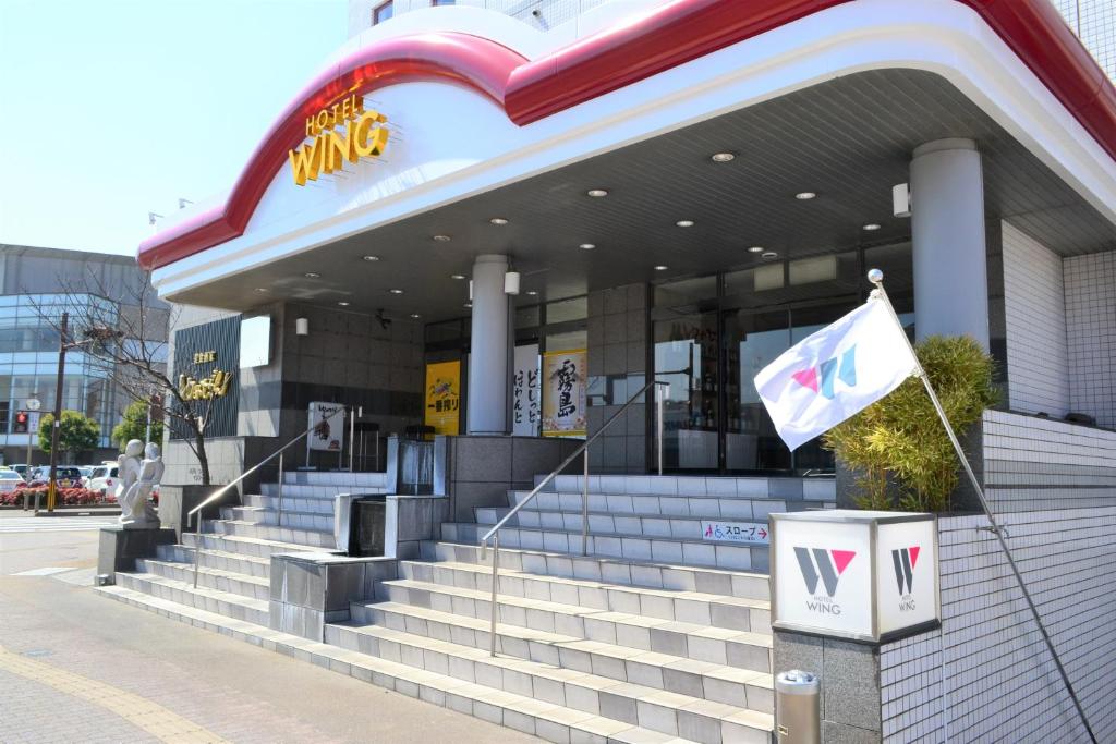 een McDonalds-gebouw met trappen en een vlag voor de deur bij Hotel Wing International Miyakonojo in Miyakonojo