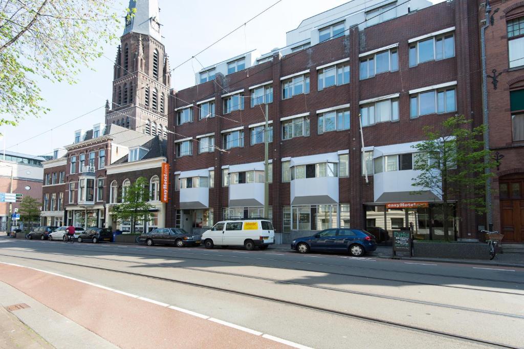eine Stadtstraße mit Autos, die vor einem Gebäude geparkt sind in der Unterkunft easyHotel The Hague City Centre in Den Haag