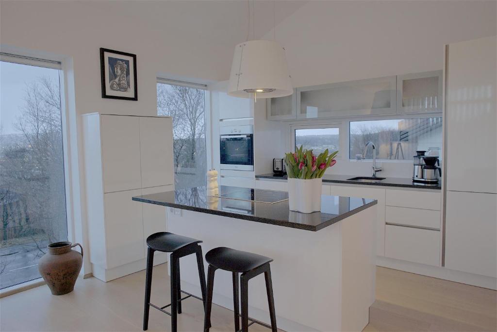 a white kitchen with two stools at a counter at Om Apartments in Reykjavík