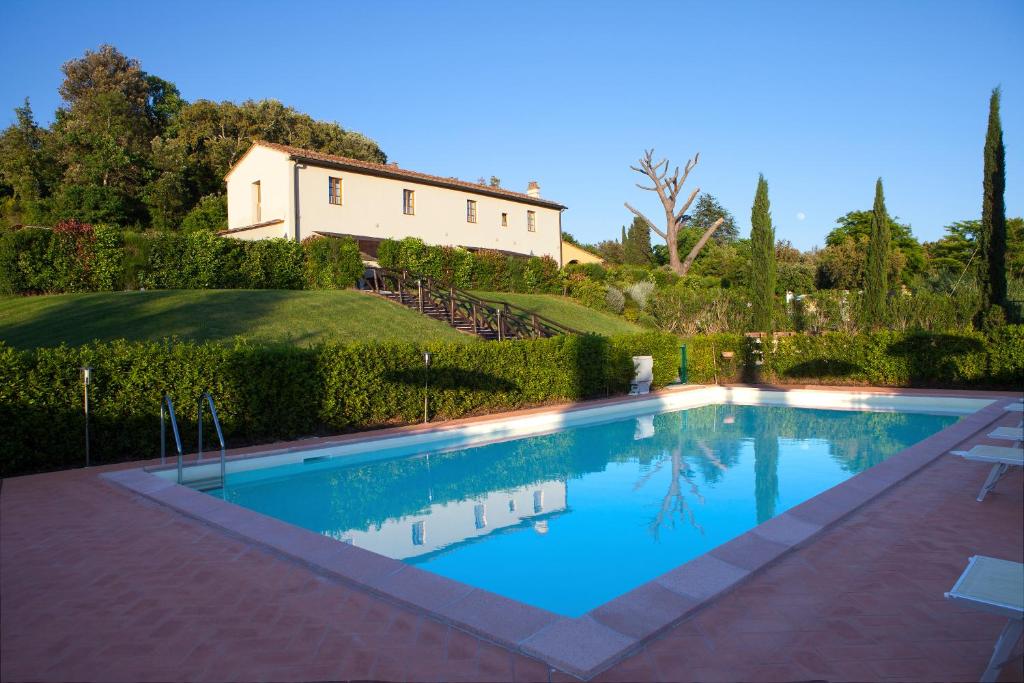 een zwembad met een huis op de achtergrond bij Casa Vacanze "Casale al Pino" in Riparbella