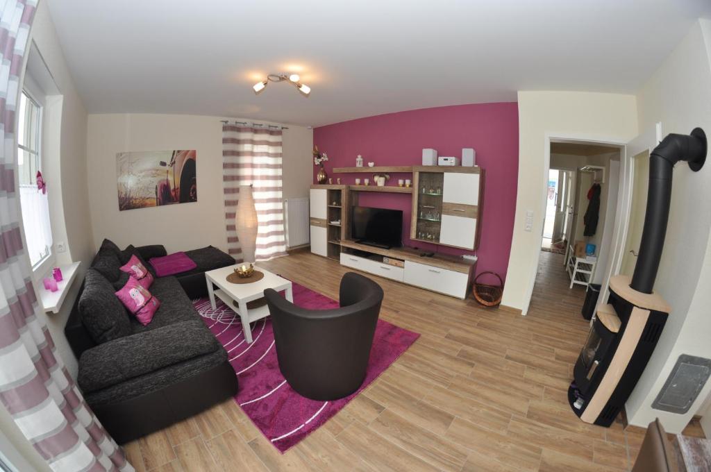 a living room with a black couch and a purple wall at Ferienhaus Müritzzauber / EG-Appartement in Marienfelde