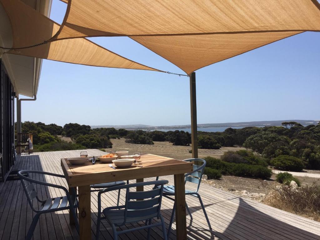 a wooden table and chairs on a deck with an umbrella at Wallaby Retreat in Kingscote