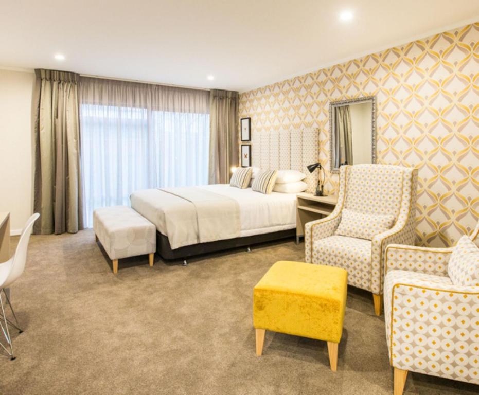a hotel room with a bed and two chairs at ASURE Destiny on Fitzherbert Motel in Palmerston North
