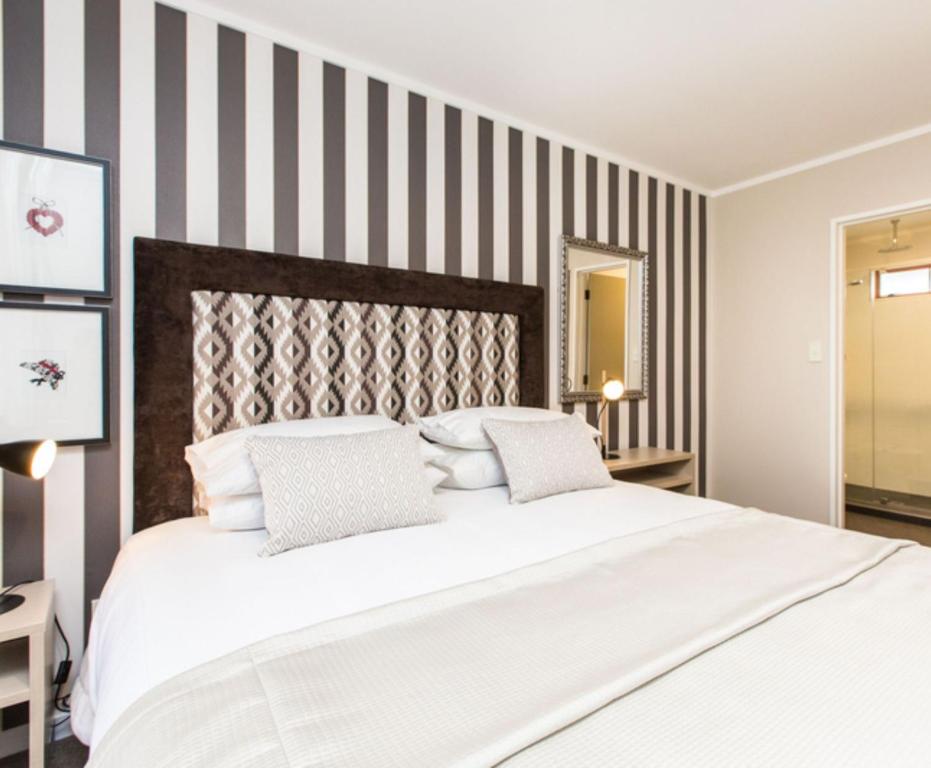 a bedroom with a large white bed with striped walls at ASURE Destiny on Fitzherbert Motel in Palmerston North