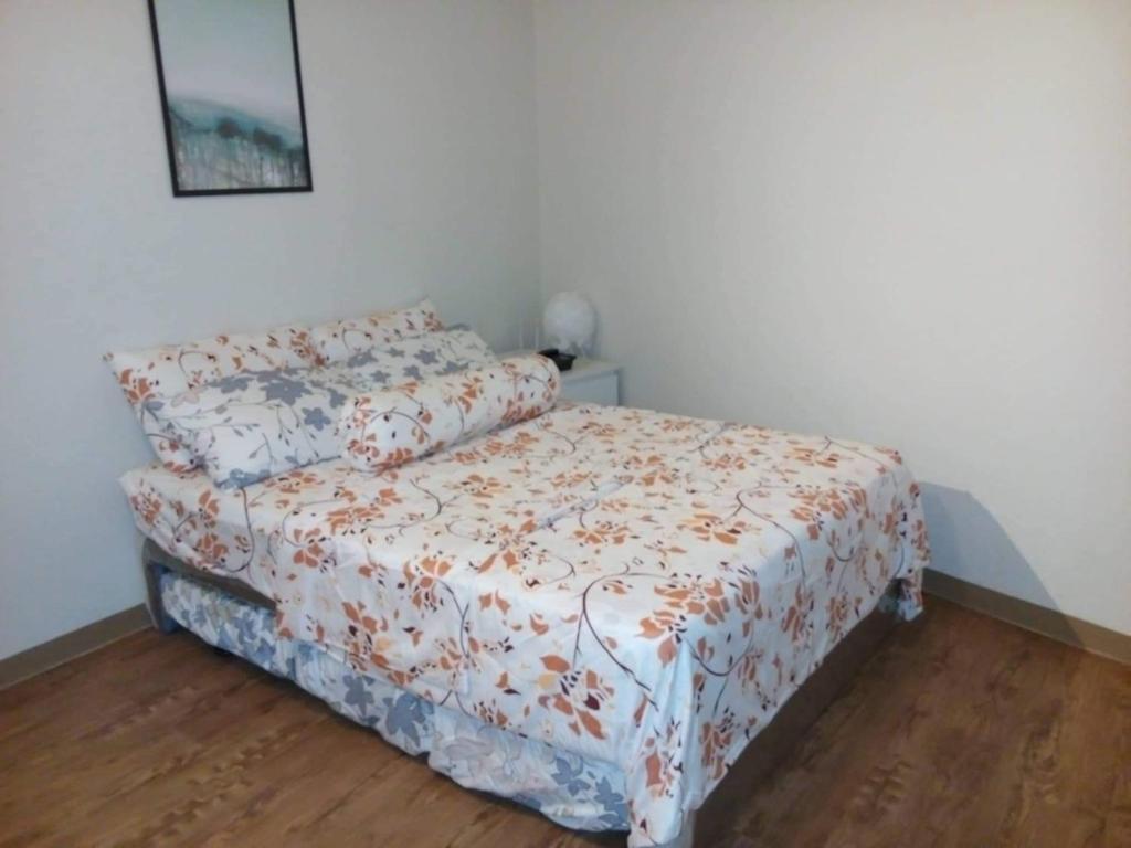 1 dormitorio con 1 cama con colcha de flores en Anya and Carl's Comfy, en Mactan