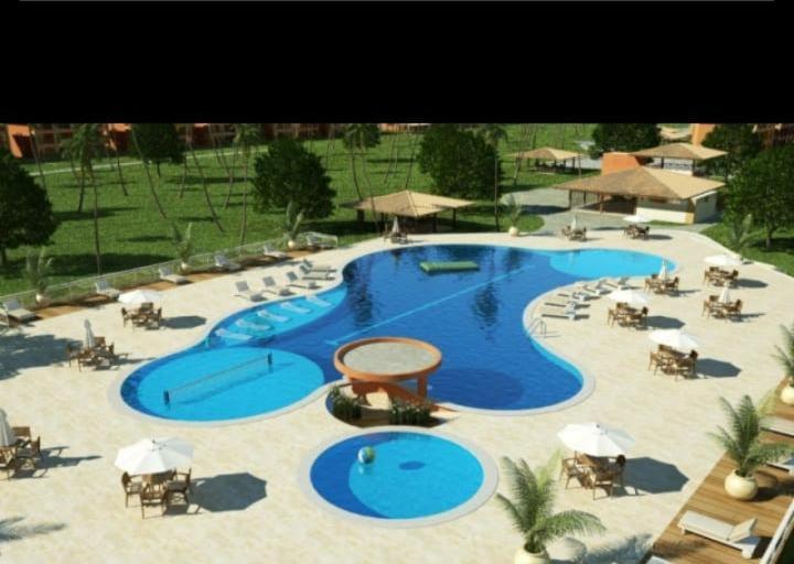 una grande piscina con sedie e ombrelloni di Condomínio Resort Villa das Águas a Estância