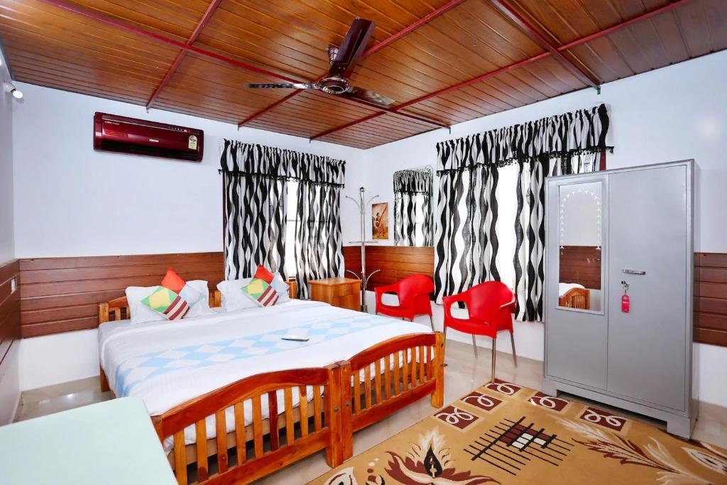 een slaapkamer met een bed en twee rode stoelen bij Honolulu Home in Cochin