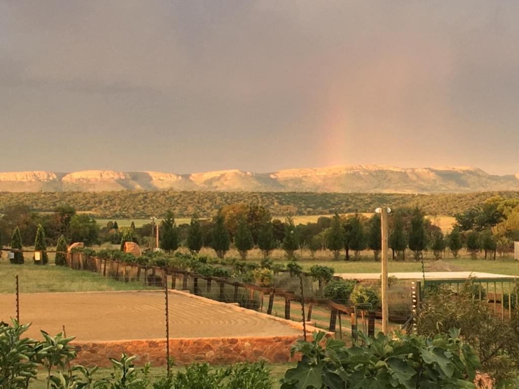 a tennis court with a rainbow in the background at Sanctuary Life Guest Farm in Magaliesburg