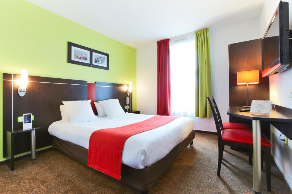 um quarto de hotel com uma cama grande e uma secretária e uma cama sidx sidx em Enzo Hotels Thionville by Kyriad Direct em Thionville