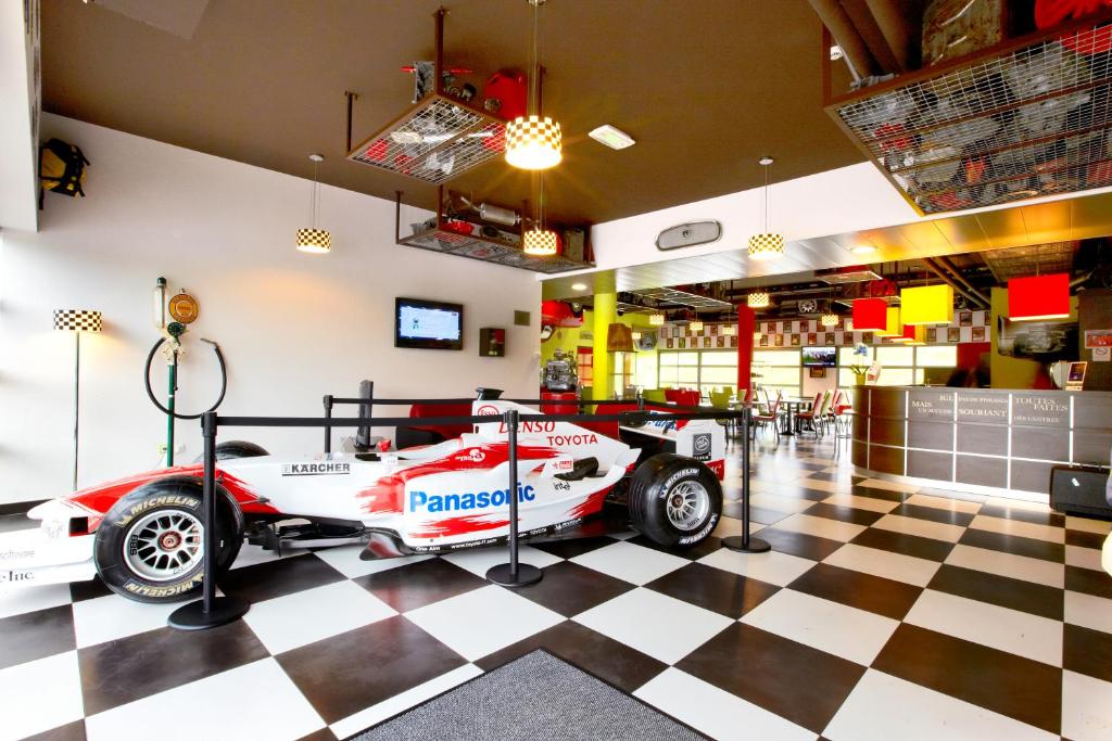 a racing car on display in a room with a checkered floor at Enzo Hotels Thionville by Kyriad Direct in Thionville